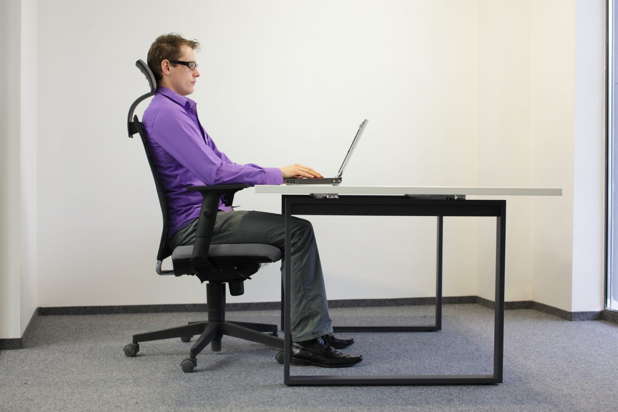 correct sitting position at workstation. man on chair working with laptop