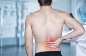 The patient stands and holds on to the spine on a blurred background.