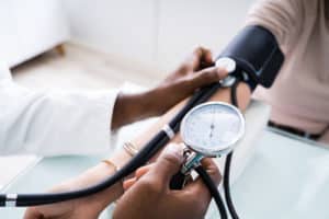 Doctor Measuring Patients Blood Pressure With Stethoscope