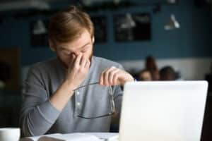 Young man at desk experiencing symptoms of Arteriovenous Malformation