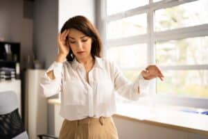 Woman in professional setting holding her head due to symptoms of brain tumor