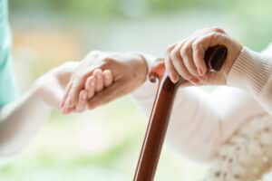 A close-up shot of an elderly woman with Parkinson’s disease holding a cane