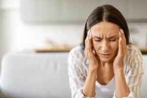 A woman with chiari malformation and a migraine rubbing her temples