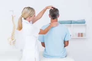 Physical therapist looking at man's spine after cervical fusion in Dallas, TX