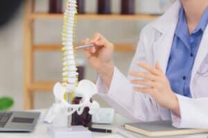 Doctor pointing to a spinal model to show connection to a neck fracture in Dallas, TX