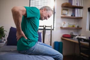 Man holding his lower back in pain due to Lumbar Fracture in Dallas, TX